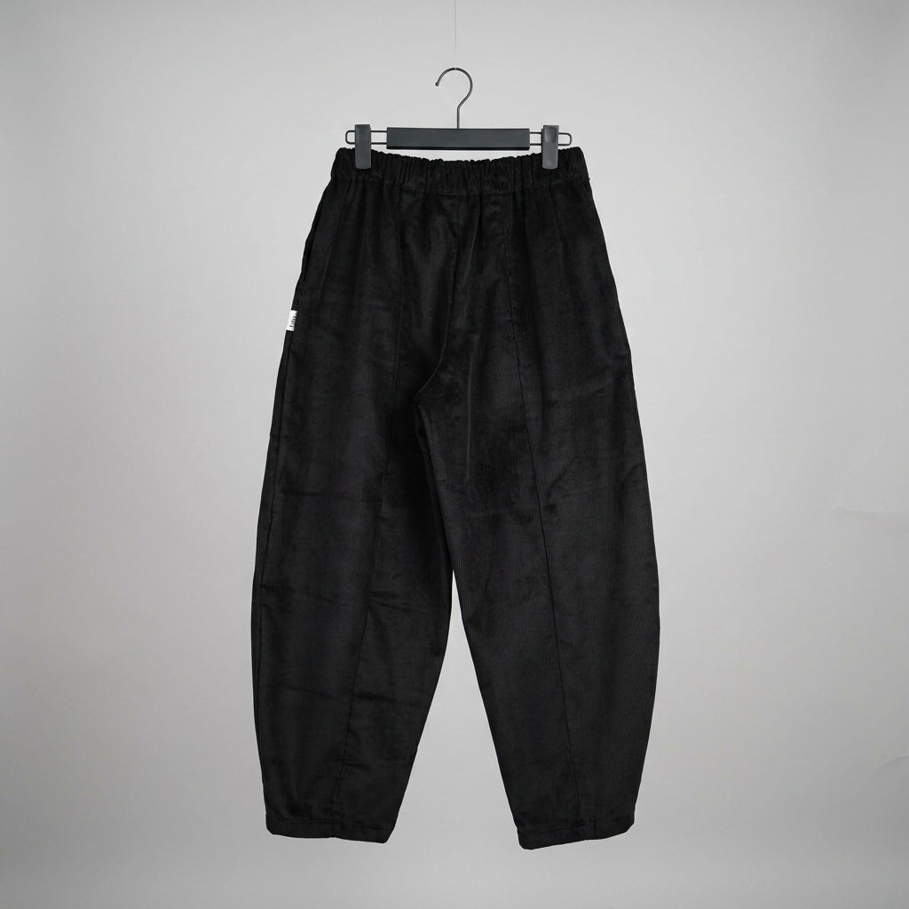 Black wide-leg cropped pants hanging from a black hanger against a white wall, with a small white graphic on the left thigh.