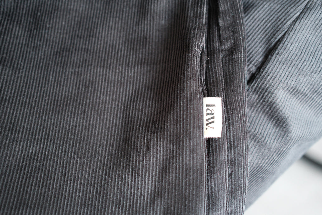 Close-up of a dark gray corduroy fabric with a small white fabric tag reading 'lav.'