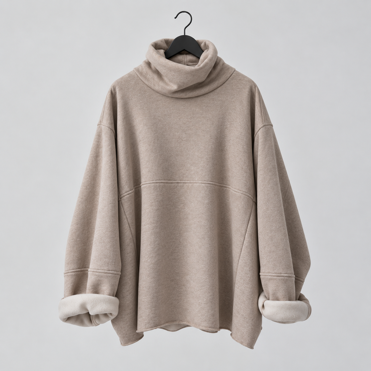 A taupe-beige oversized turtleneck sweatshirt with a soft cream-colored fleece lining visible at the cuffs, hanging on a black hanger against a light gray background.