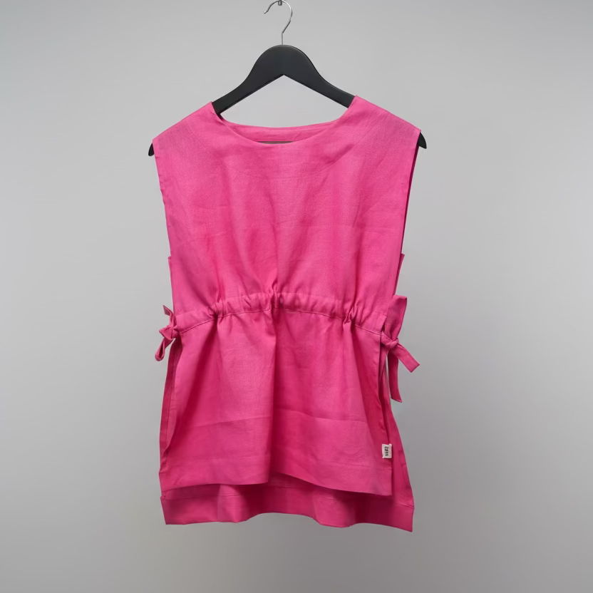 Pink sleeveless top on a hanger against a white wall