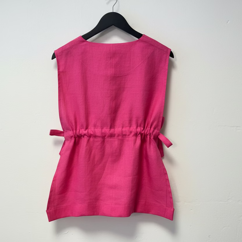 Pink sleeveless top on a hanger against a white background