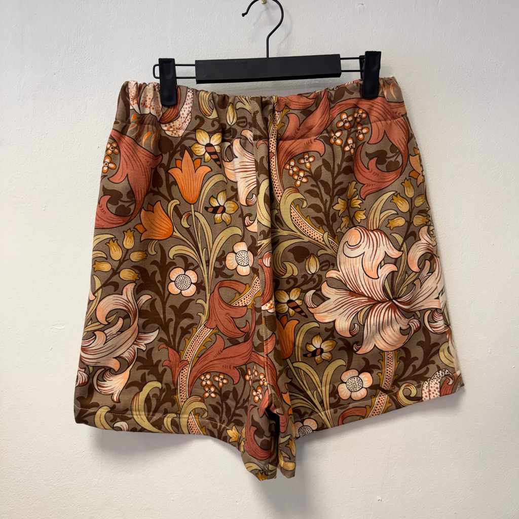 Floral patterned shorts on a hanger against a white background
