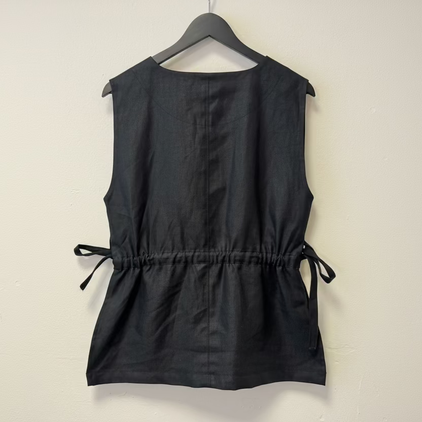 Black sleeveless top on a hanger against a plain background