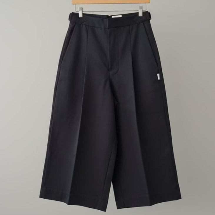 Black wide-leg pants on a hanger against a gray background