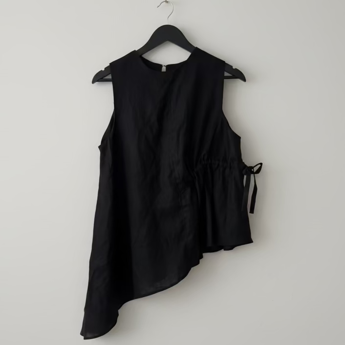 Black sleeveless top on a hanger against a white wall