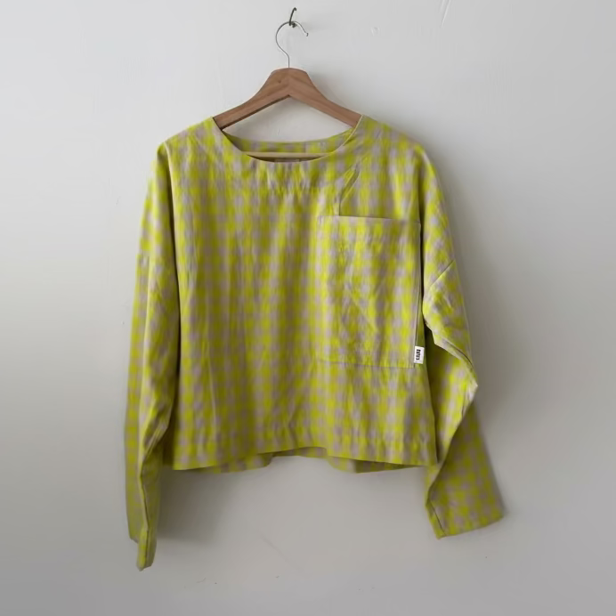Yellow checkered shirt on a hanger against a white wall