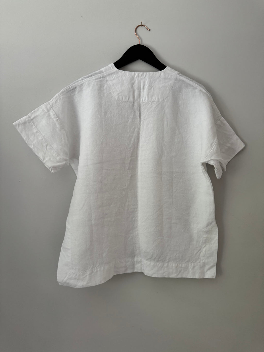 White shirt on a hanger against a gray background