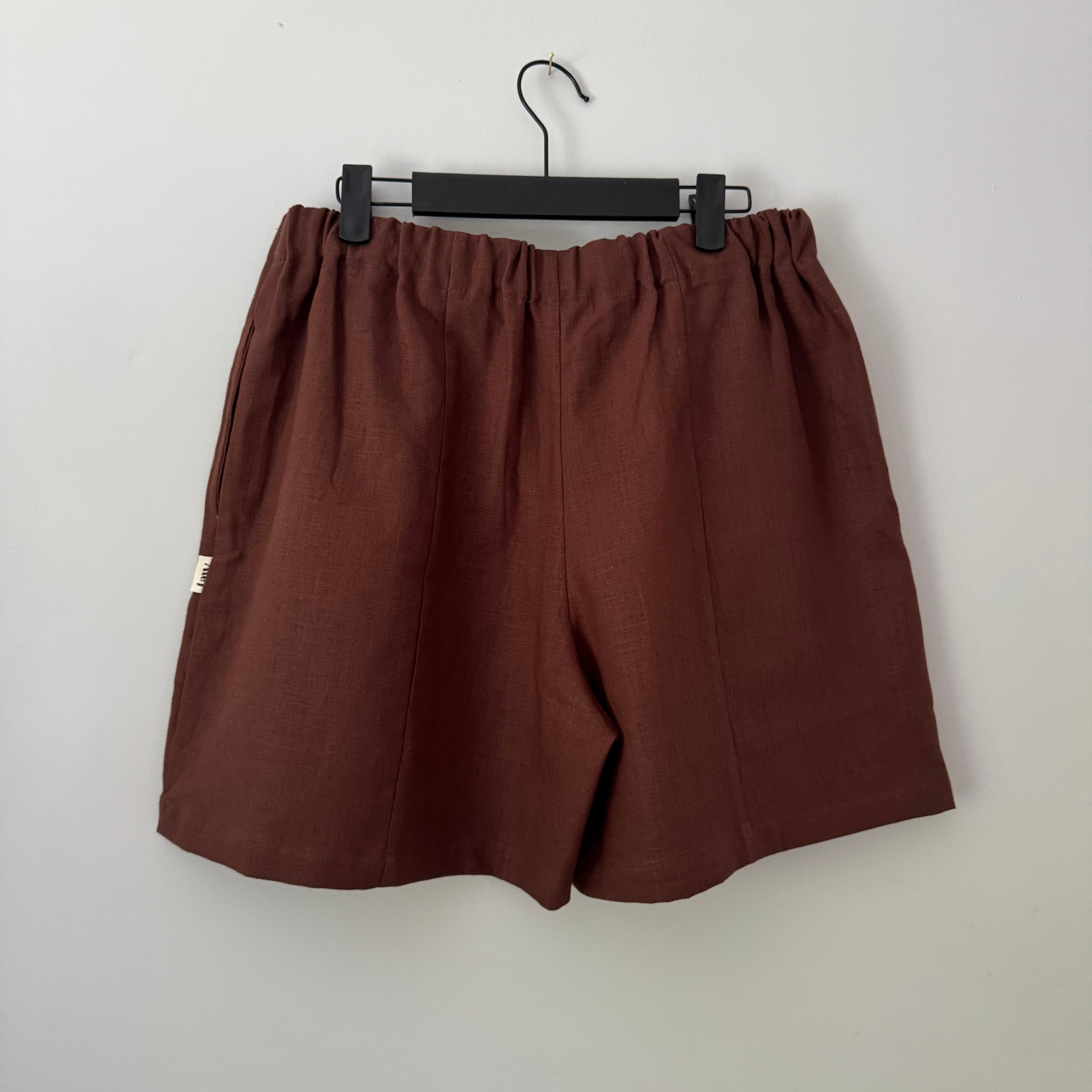 Brown shorts on a hanger against a white background