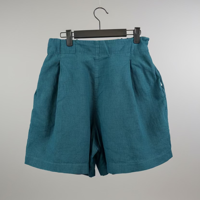 Teal shorts on a hanger against a plain background