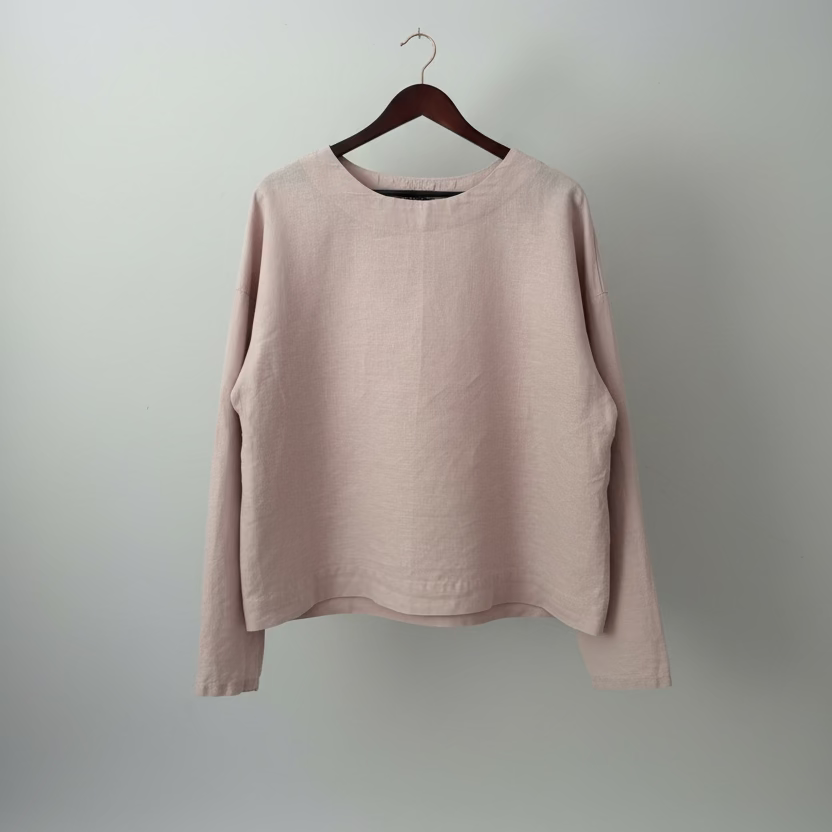 Pink long-sleeve shirt on a hanger against a white wall