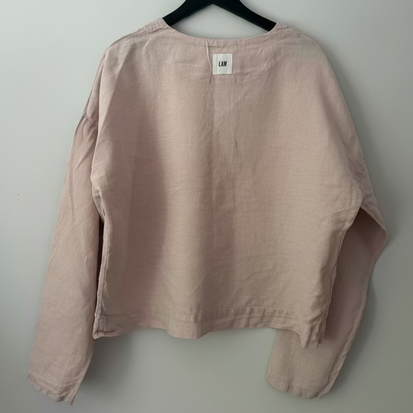 Pink shirt on a hanger against a plain background