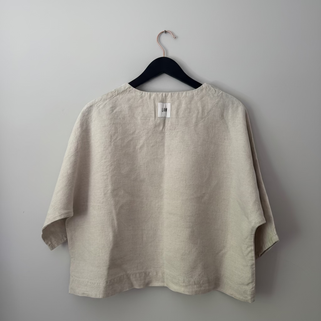 Beige shirt on a hanger against a plain background