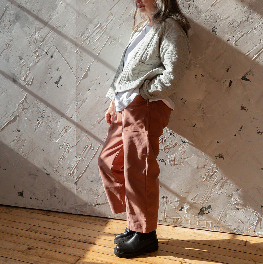 Person standing in a room with sunlight casting shadows on the wall
