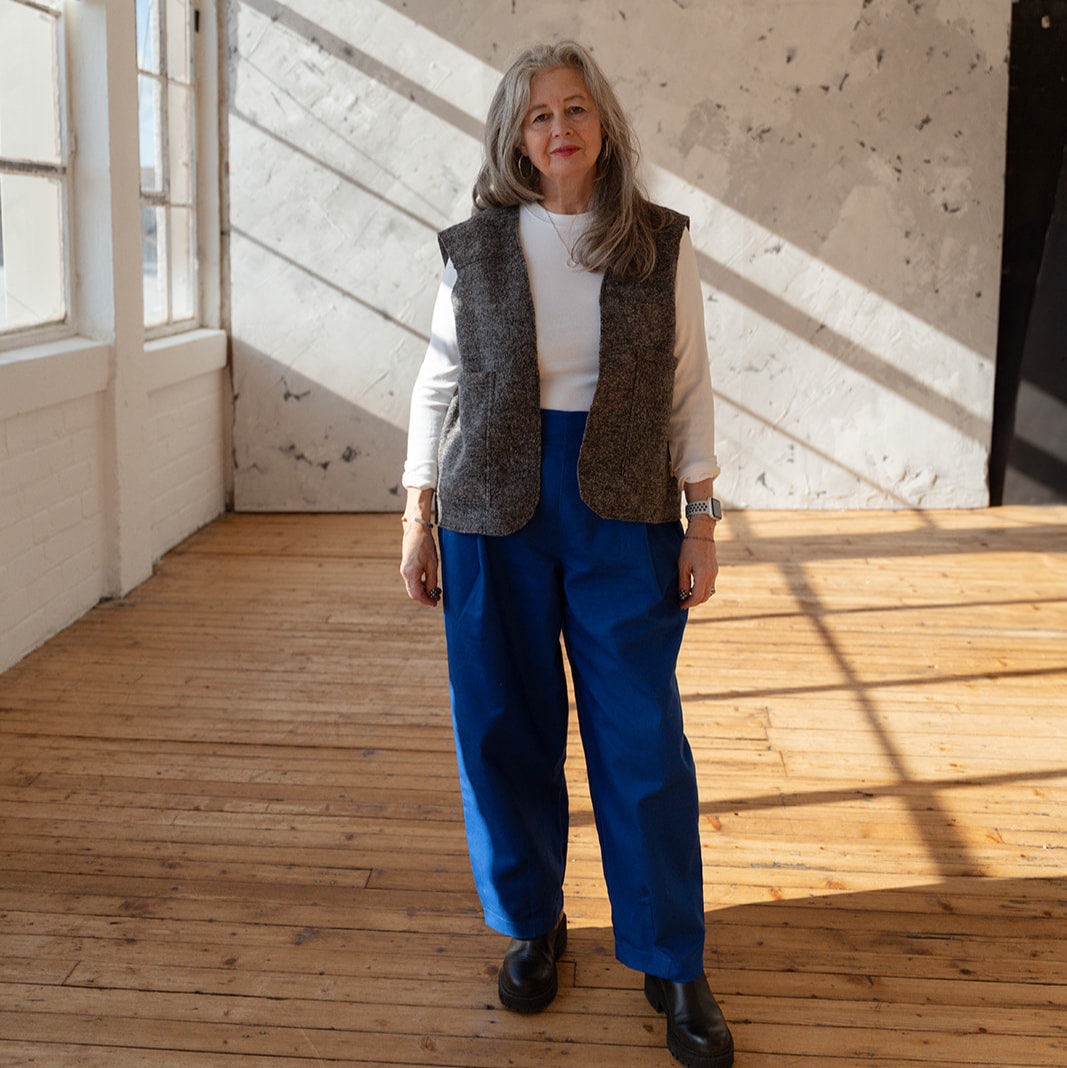 Person standing in a room with wooden floor and white walls