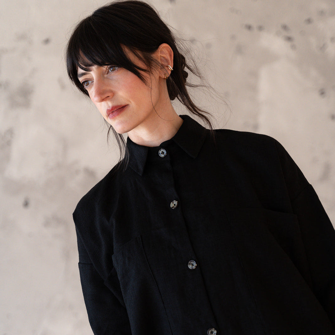 Woman wearing a black coat against a textured wall