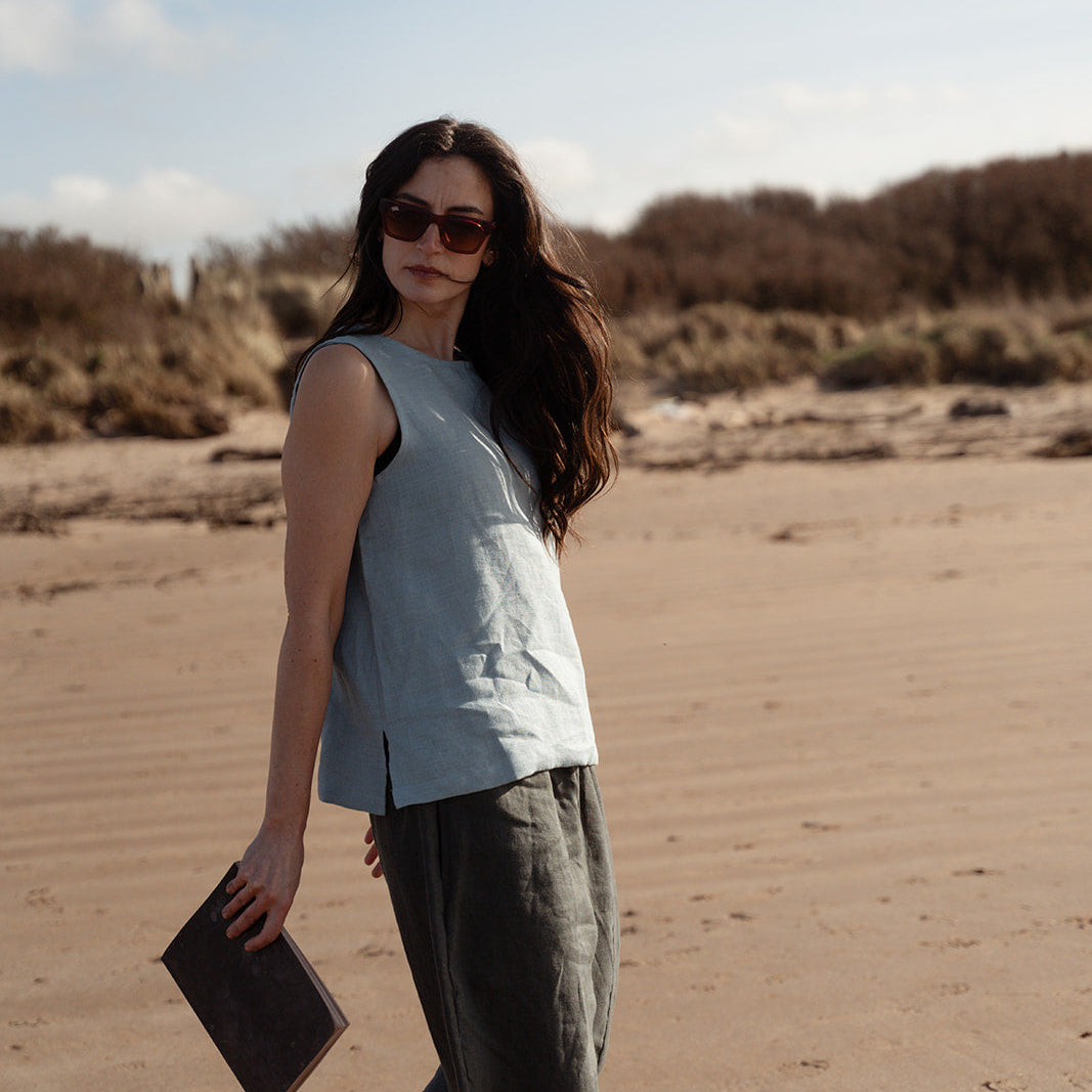 girl wearing light blue linen top on the beach