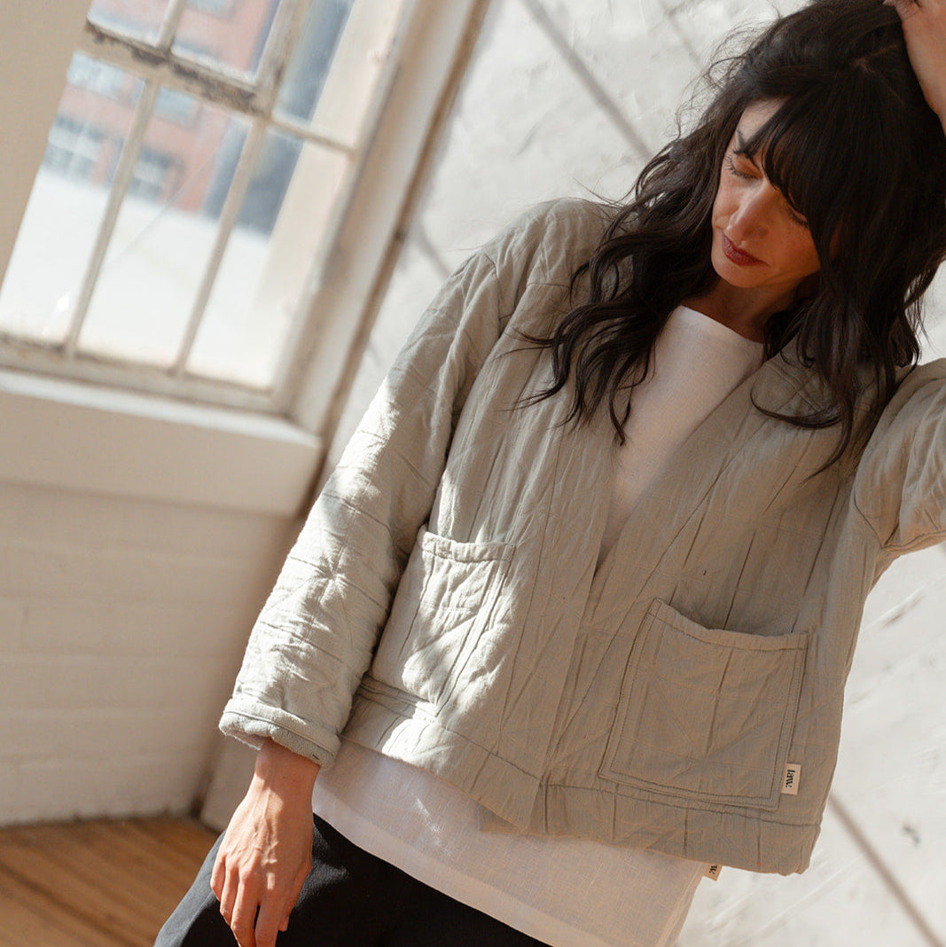 Woman wearing a beige quilted jacket in a sunlit room