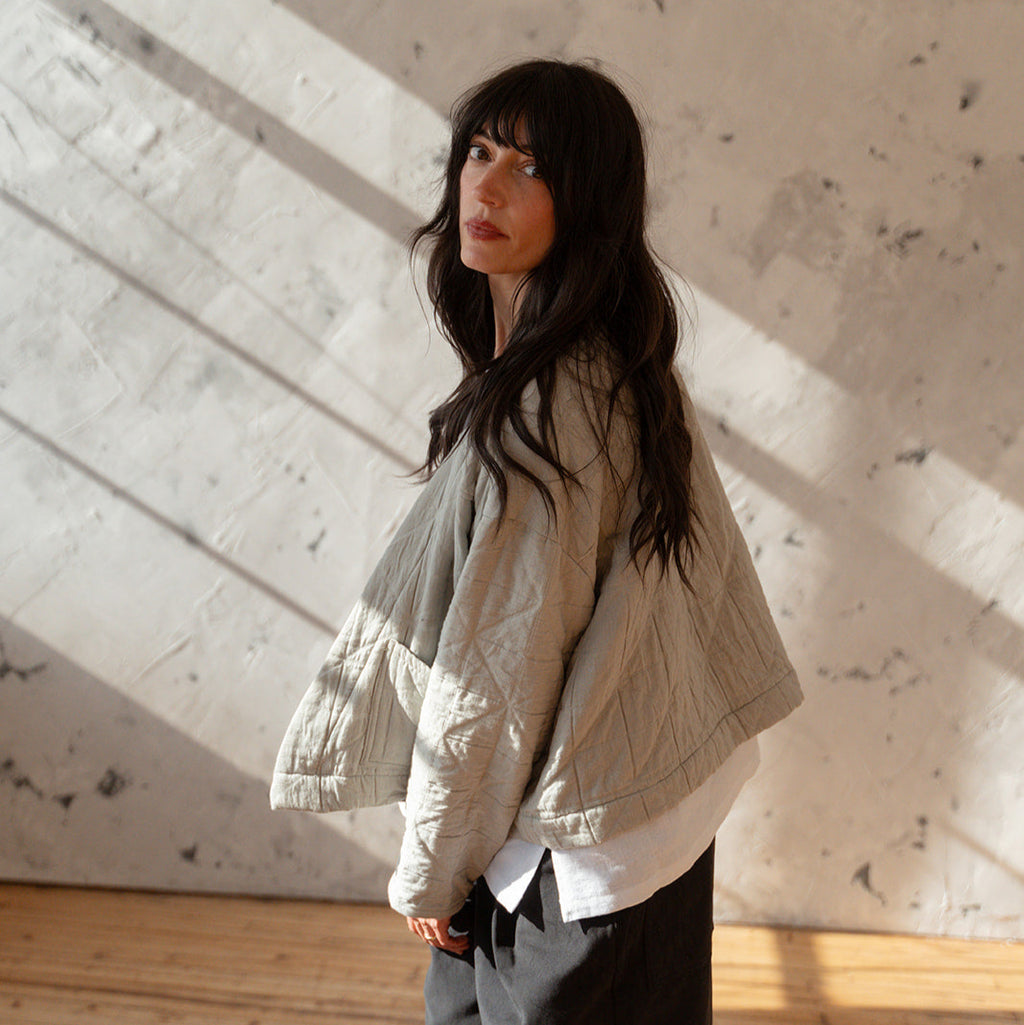 LAW Design studio Person wearing a light-colored jacket and dark pants standing against a textured wall.