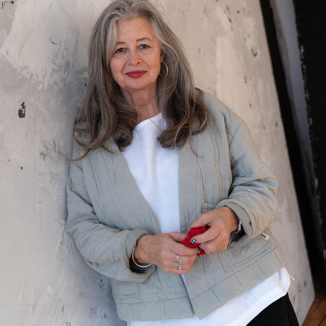 Woman standing against a textured wall holding a red phone.