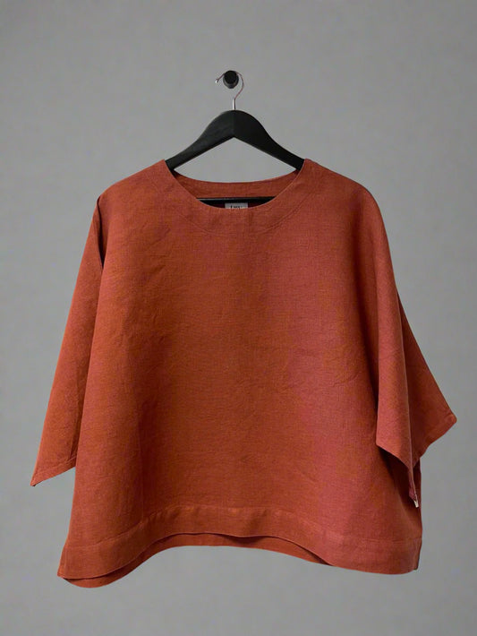 Orange sweater on a hanger against a white wall