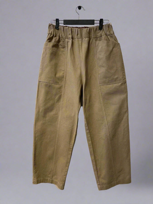 Beige pants hanging on a hanger against a white background