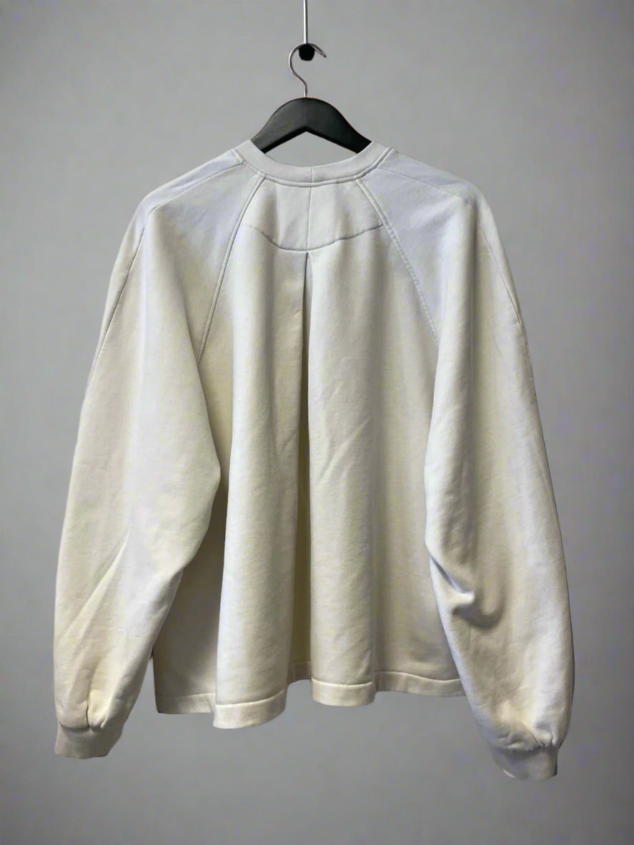 White sweatshirt on a hanger against a plain wall